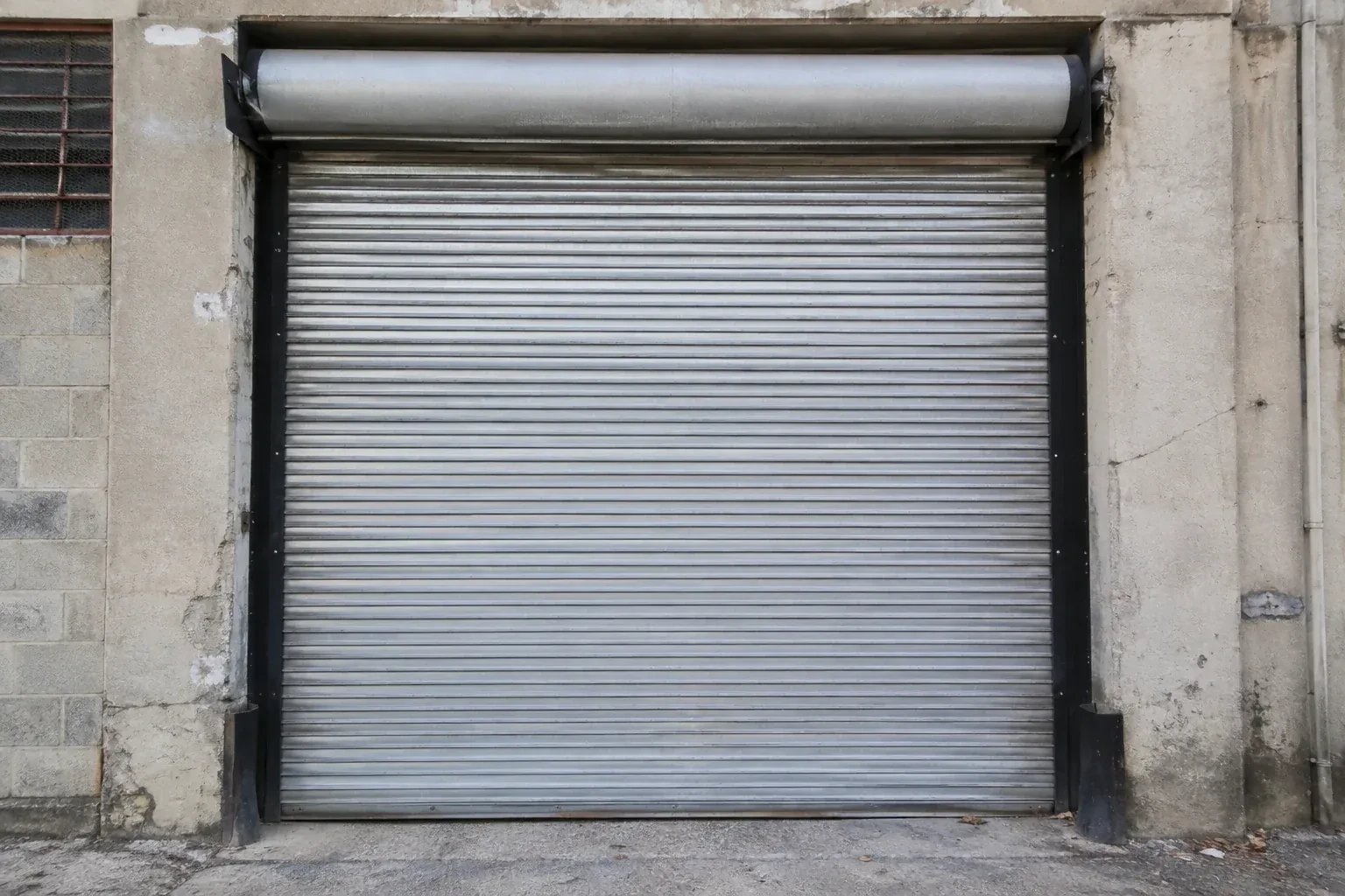 Closed metal rolling shutter in a weathered warehouse opening. — Commercial Rolling Door Repair, King